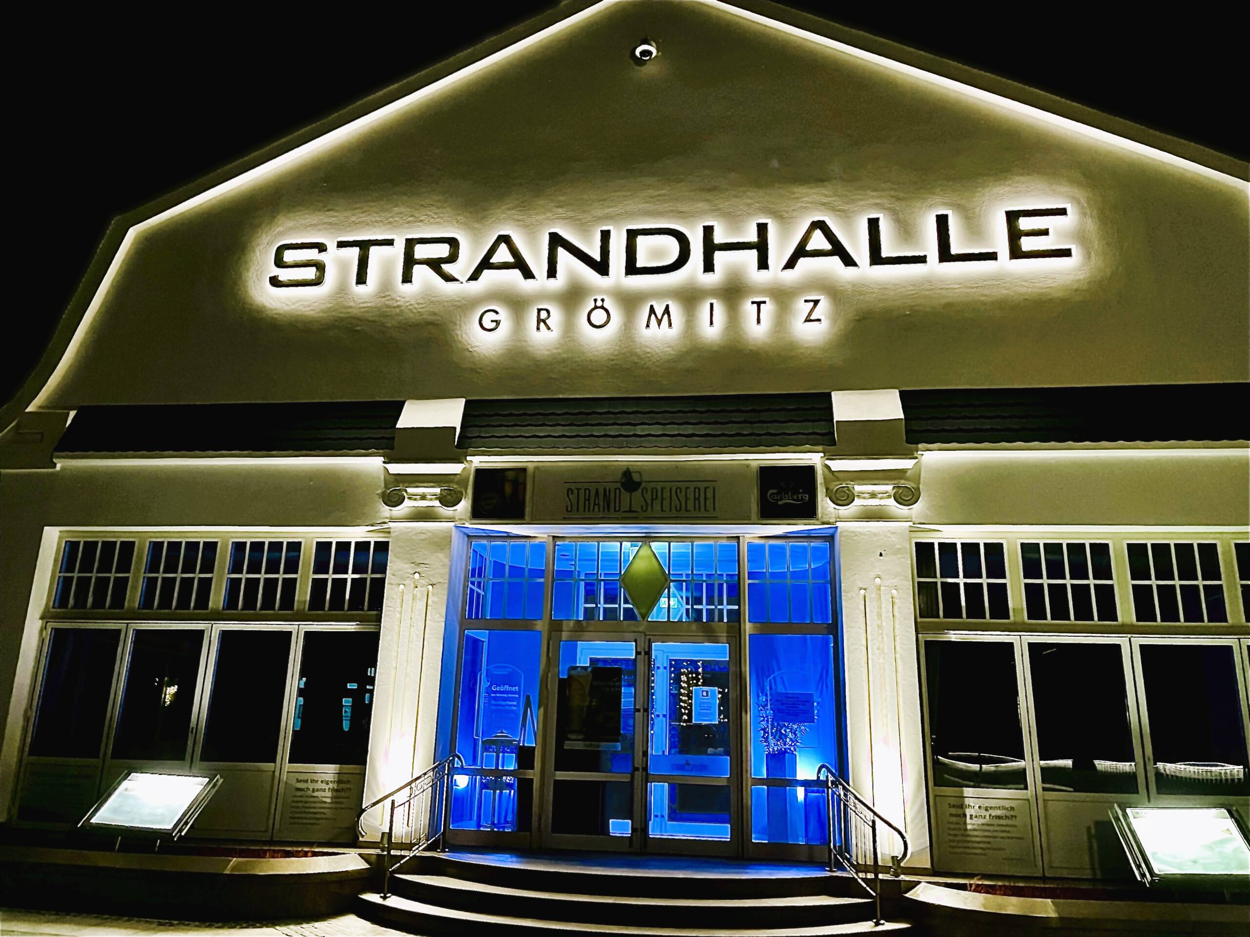 Bild der beleuchteten Front der Strandhalle Grömitz im dunkeln
